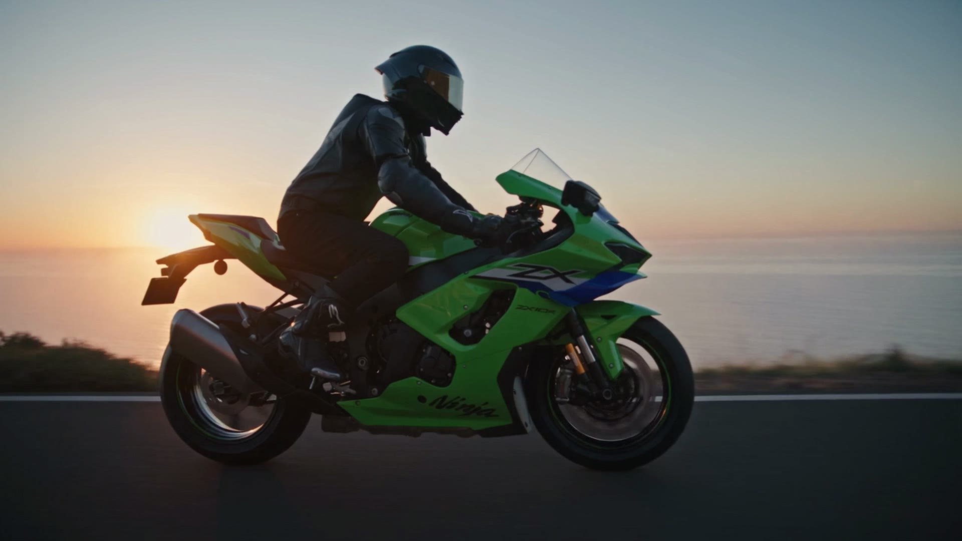 A green sports motorcycle parked on gravel at sunset