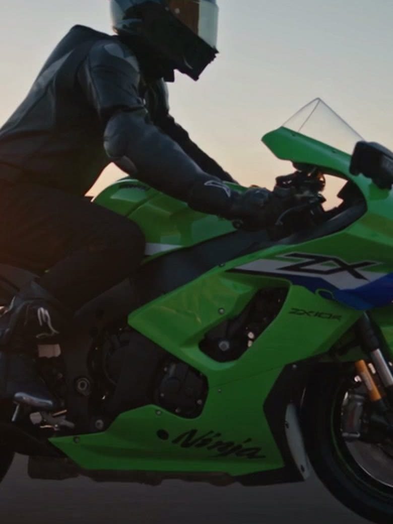 A green sports motorcycle parked on gravel at sunset