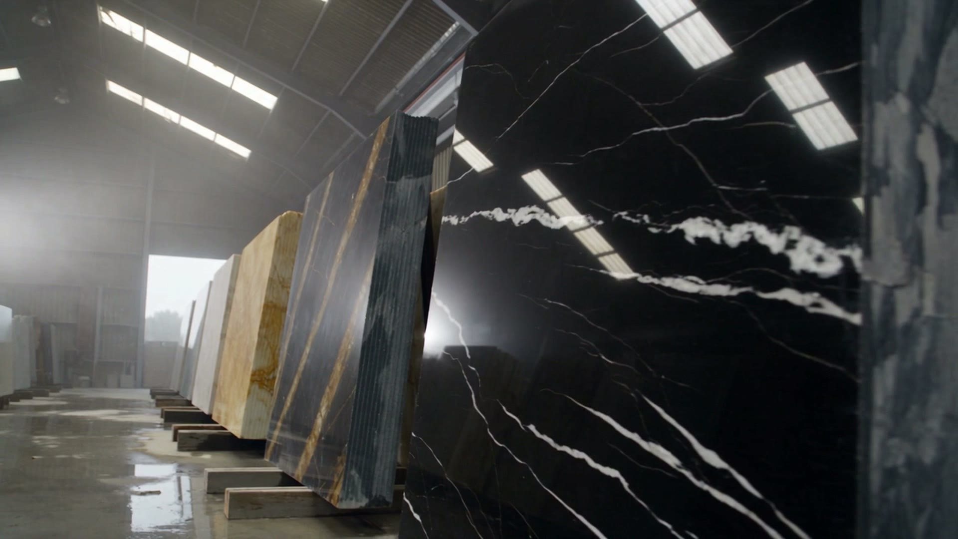 A black and gold Portoro marble block in a dim workshop