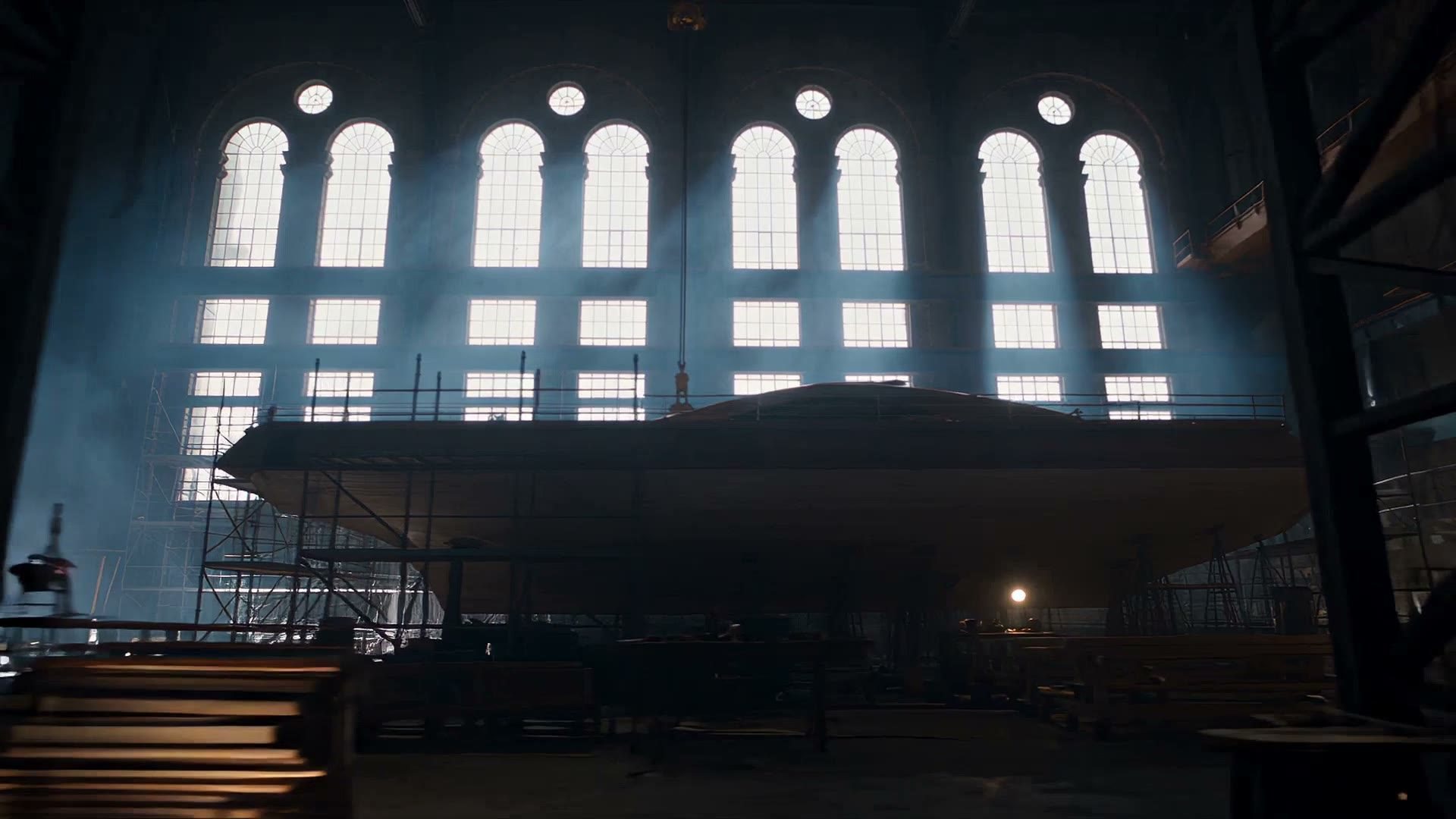 A hull on scaffolding inside the shed, backlit through arched windows