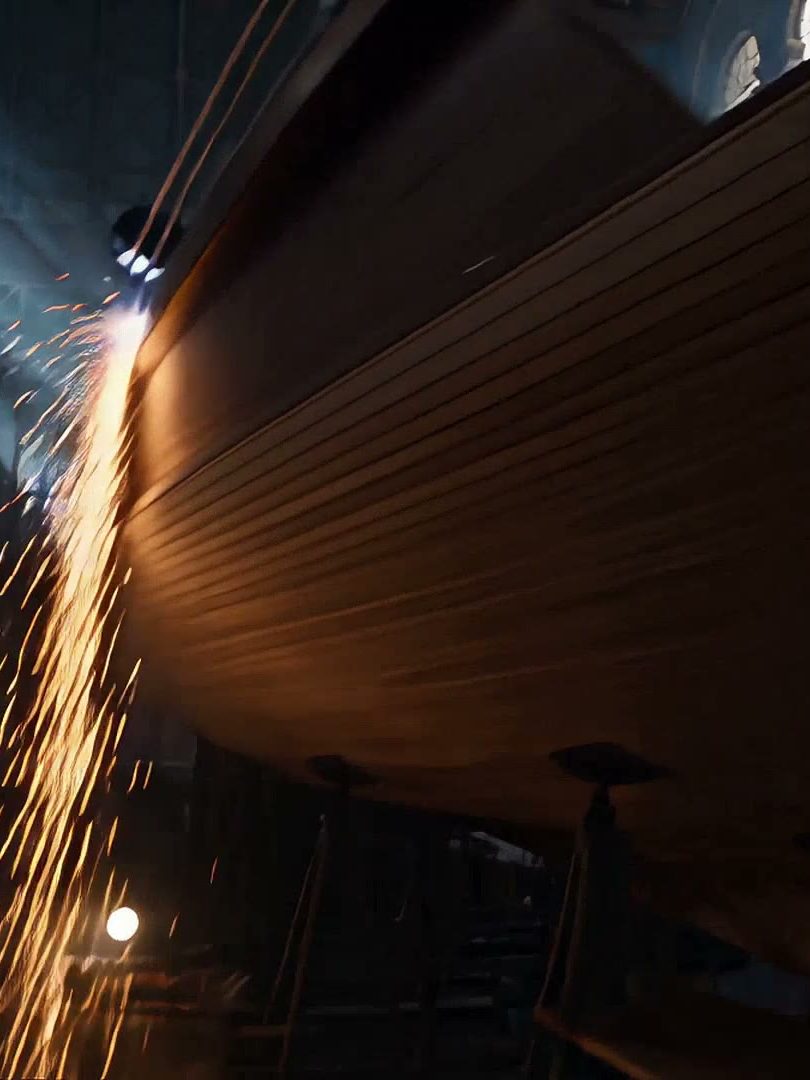 A hull on scaffolding inside the shed, backlit through arched windows