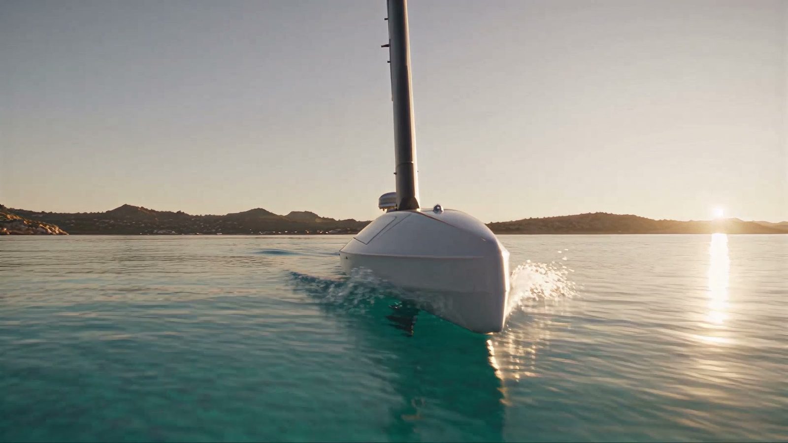 A sailing drone below a granite coast in low light, seen from the water