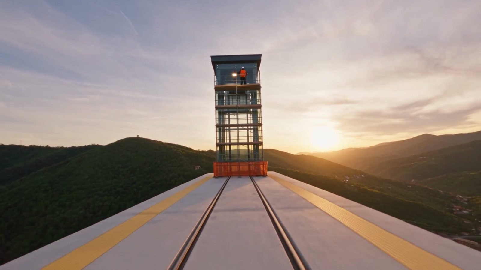 The glass and steel tower of a panoramic lift at sunset