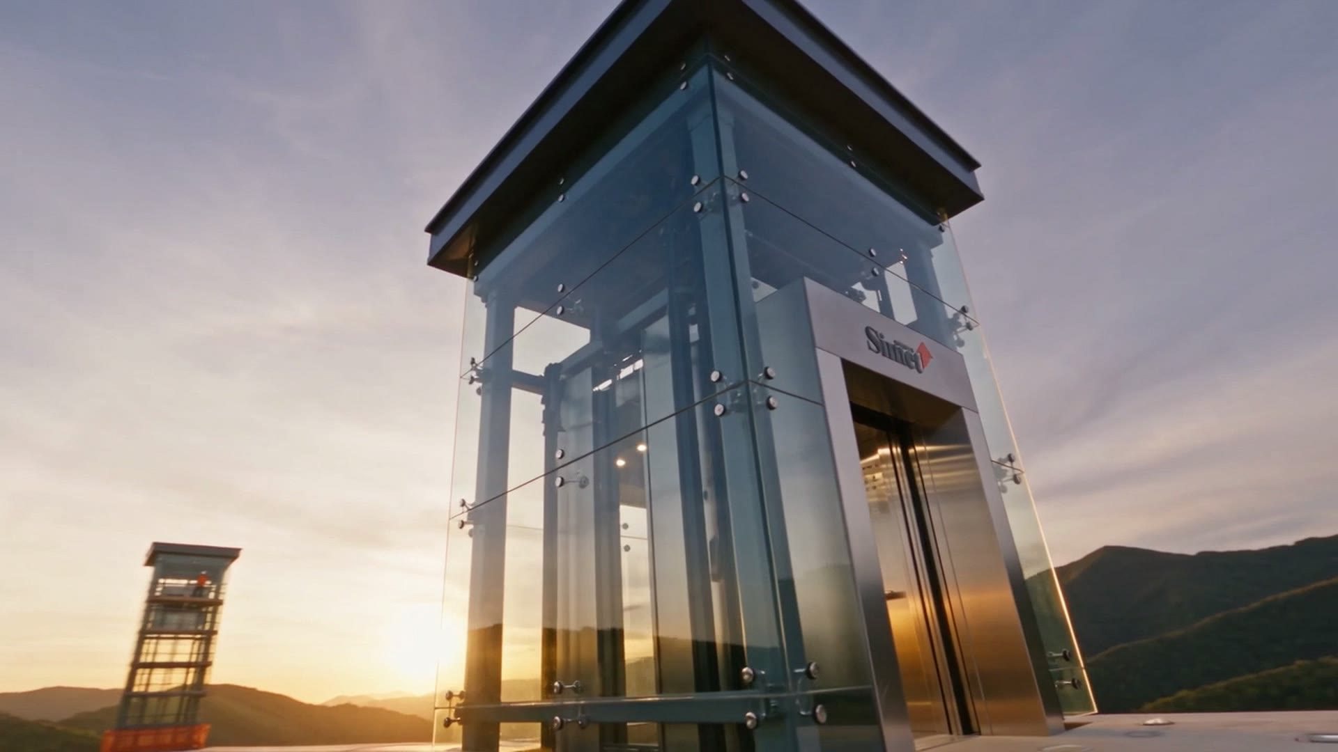The glass and steel tower of a panoramic lift at sunset